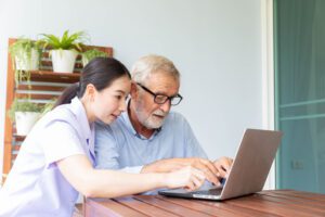 Woman sitting with older adult and looking at a laptop